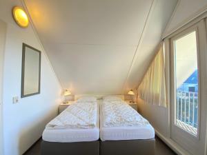 Un dormitorio pequeño con dos camas y una ventana. en Previnaireweg 24, en Callantsoog