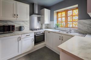 cocina con armarios blancos, fregadero y ventana en Host & Stay - Tripps Mews en Mánchester