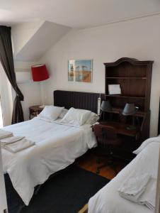 リスボンにあるMigas Lisbon Houseのベッドルーム1室(ベッド2台、ランプ付きデスク付)