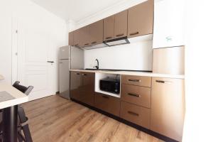 eine Küche mit braunen Schränken und einer Mikrowelle in der Unterkunft Aparthotel Mirage Sunset - zona Hotel Rex in Mamaia + 9 Fotos