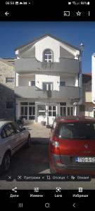 un edificio blanco con dos coches estacionados frente a él en Vila Centar en Trebinje