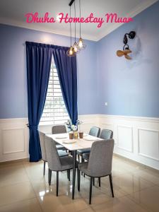 a dining room with blue walls and a table and chairs at Dhuha Homestay Muar in Muar