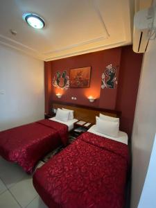 two beds in a room with red walls at Bano Palace Hotel in Douala