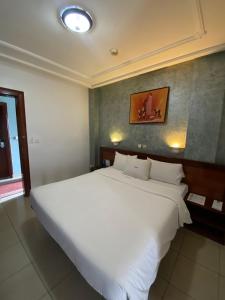 een slaapkamer met een groot wit bed in een kamer bij Bano Palace Hotel in Douala