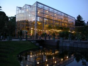 een groot glazen gebouw met verlichting voor een vijver bij Golden Tulip Leiden Centre in Leiden