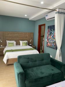 een slaapkamer met een bed en een groene bank bij Bano Palace Hotel in Douala