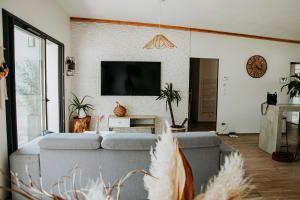 un soggiorno con un divano e una TV di La Villa Ô Bois - Billard & Baby-Foot - face à la forêt a Séméac