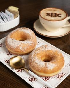 dos donuts y una taza de café sobre una mesa en Surat Marriott Hotel, en Surat