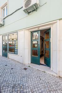 uma frente de loja com portas verdes numa rua em Bela Vista B em Lisboa
