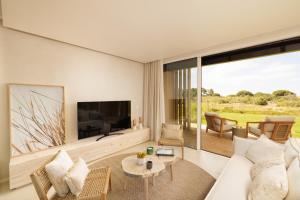 a living room with a white couch and a tv at Verdelago Resort in Praia Verde