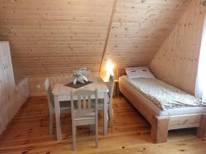 a dining room with a table and a bed in a attic at Wypoczynek nad stawami in Sobiechy