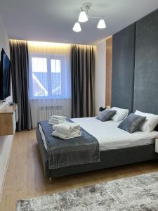a bedroom with two beds and a large window at Altai Apartments in Astana