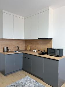 a kitchen with white cabinets and a microwave at Altai Apartments in Astana +23 photos