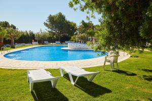two white chairs sitting next to a swimming pool at Alannia Costa Dorada in Platja de l’Almadrava