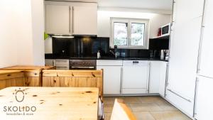 a kitchen with white cabinets and a wooden table at Haus Cotton 4.5 Room Apartment in Breiten