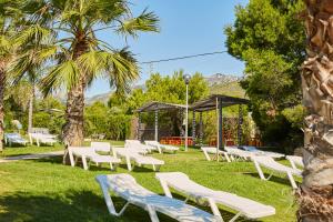 a group of white lounge chairs in the grass at Alannia Costa Dorada in Platja de l’Almadrava