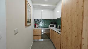 a kitchen with white cabinets and green walls at Jerónimos Apartments best place in Lisbon - 1º D in Lisbon