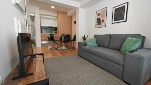 a living room with a gray couch and a television at Jerónimos Apartments best place in Lisbon - 1º D in Lisbon