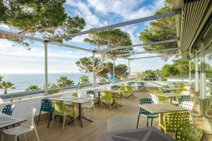 an outdoor patio with tables and chairs and the ocean at Alannia Costa Dorada in Platja de l’Almadrava