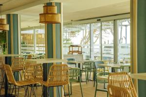 a restaurant with tables and chairs and windows at Alannia Costa Dorada in Platja de l’Almadrava
