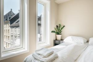 a white bed in a room with a window at Stay Urban - Scandinavian Comfort with Private Balcony in Bergen