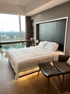 een slaapkamer met een groot bed en een stoel bij U Residence 2 Studio Apartment POOL VIEW in Tangerang