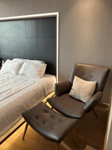 una silla junto a una cama con almohada en U Residence 2 Studio Apartment POOL VIEW, en Tangerang
