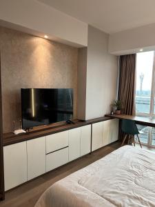 1 dormitorio con TV de pantalla plana grande en la pared en U Residence 2 Studio Apartment POOL VIEW, en Tangerang