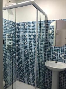 a blue tiled bathroom with a sink and a shower at Hotel Natal in Santos