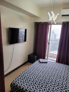- une chambre avec un lit et une télévision à écran plat dans l'établissement Juja's place, à Manille