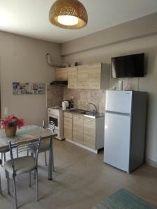 a kitchen with a white refrigerator and a table with chairs at Κατηγιώργης Ξενώνας Ρεγγίνα in Agios Georgios