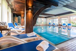 a pool in a house with blue chairs and a swimming pool at Hotel Krone Igelsberg in Freudenstadt