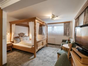 Hotel Garni Ferienhof في مايرهوفن: غرفة نوم مع سرير مظلة وتلفزيون