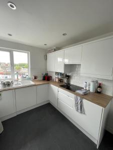 a white kitchen with white cabinets and a sink at 2BD Flat with Views of Canary Wharf - Rotherhithe in London