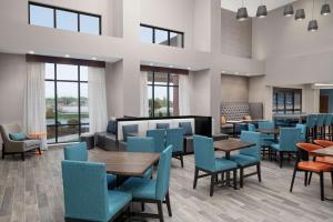 a waiting room with tables and chairs and windows at Hampton Inn & Suites Bridgeview Chicago, Il in Bridgeview