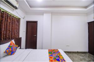 a bedroom with a bed and a wooden door at FabHotel Rani Tower in Kolkata