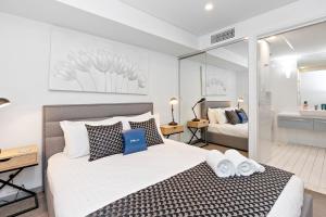 a bedroom with a large bed and a bathroom at Lily - North Terrace Cityscape Residence in Adelaide
