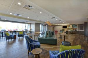 a lobby with blue chairs and tables and a cafeteria at Home2 Suites By Hilton Dayton South in Miamisburg