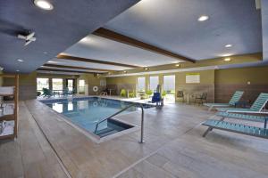 Una piscina en una habitación grande con sillas y mesas. en Home2 Suites By Hilton Dayton South, en Miamisburg