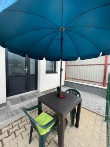 stół i krzesło z niebieskim parasolem w obiekcie Ianis Home w mieście Cristeşti