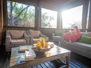 a woman sitting on a porch reading a book at Buffalo Rock Tented Camp in Hazyview