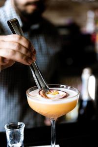 a person stirring a cocktail in a martini glass at The Londoner Hotel Sliema in Sliema