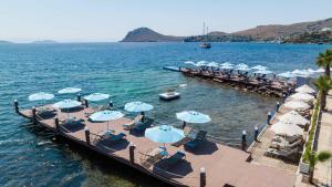 a dock with chairs and umbrellas in the water at Elite Hotel Yalıkavak in Yalıkavak