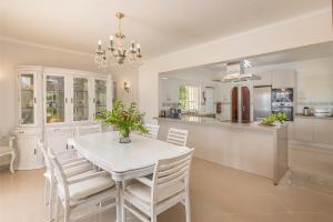 Casa da Praia في فيريغودو: مطبخ وغرفة طعام مع طاولة وكراسي بيضاء