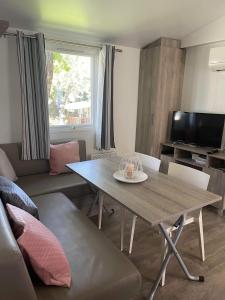 uma sala de estar com uma mesa e um sofá em Mobilhome ´Sandra ´ em Lagorce