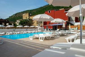 uma piscina com cadeiras brancas e guarda-sóis em I Milord 2 em Castel San Giorgio