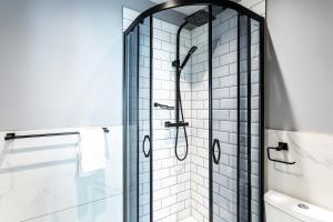 a bathroom with a shower with a glass door at Kensington Rooms - Philbeach Gardens in London