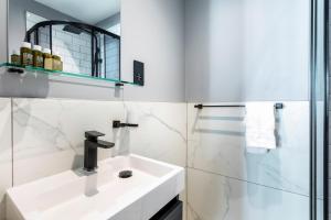 baño blanco con lavabo y ducha acristalada en Kensington Rooms - Philbeach Gardens, en Londres