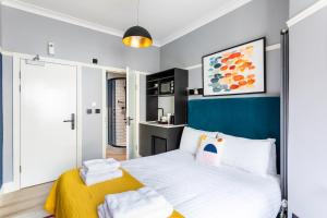a bedroom with a bed with a blue headboard at Kensington Rooms - Philbeach Gardens in London