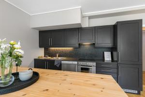 a kitchen with black cabinets and a wooden table at Beautiful apartment with 3 bedrooms in Sogndal